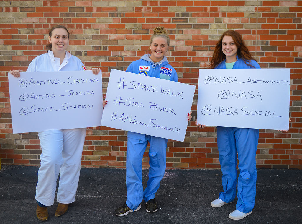 Madison Reiss, Sam Schupp, and Katy Parcell hold up signs